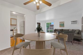 a living room with a ceiling fan and a dining table with four chairs